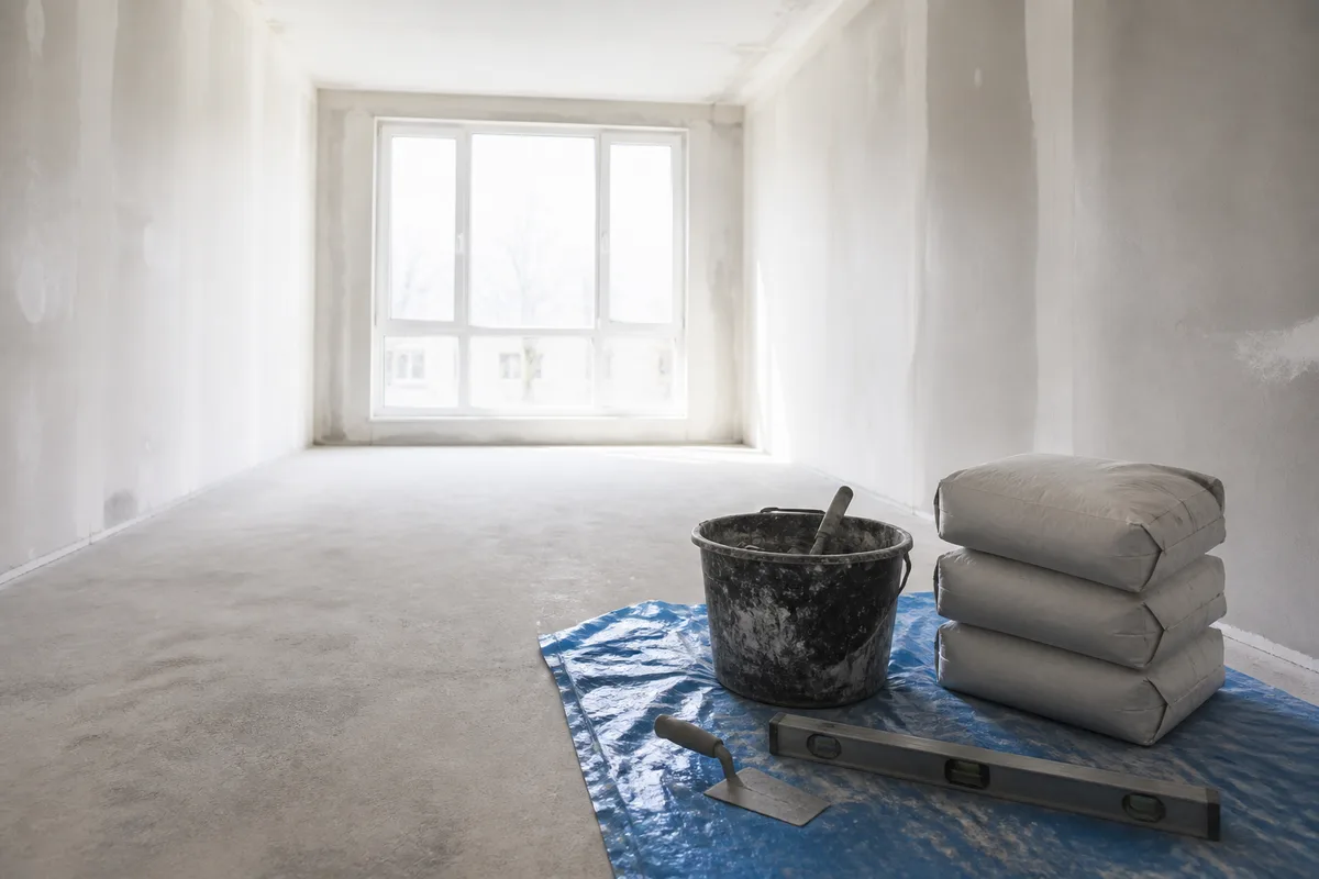 Chantier de renovation interieure avec sacs de mortier et outils de macon poses au sol