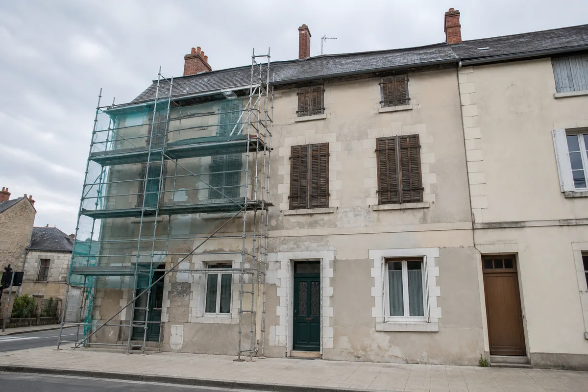 Facade de maison de ville en cours de ravalement avec un echafaudage monte sur une partie du mur