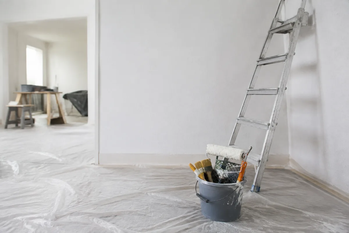 Chantier de rénovation intérieure avec bâches de protection et outils posés au sol