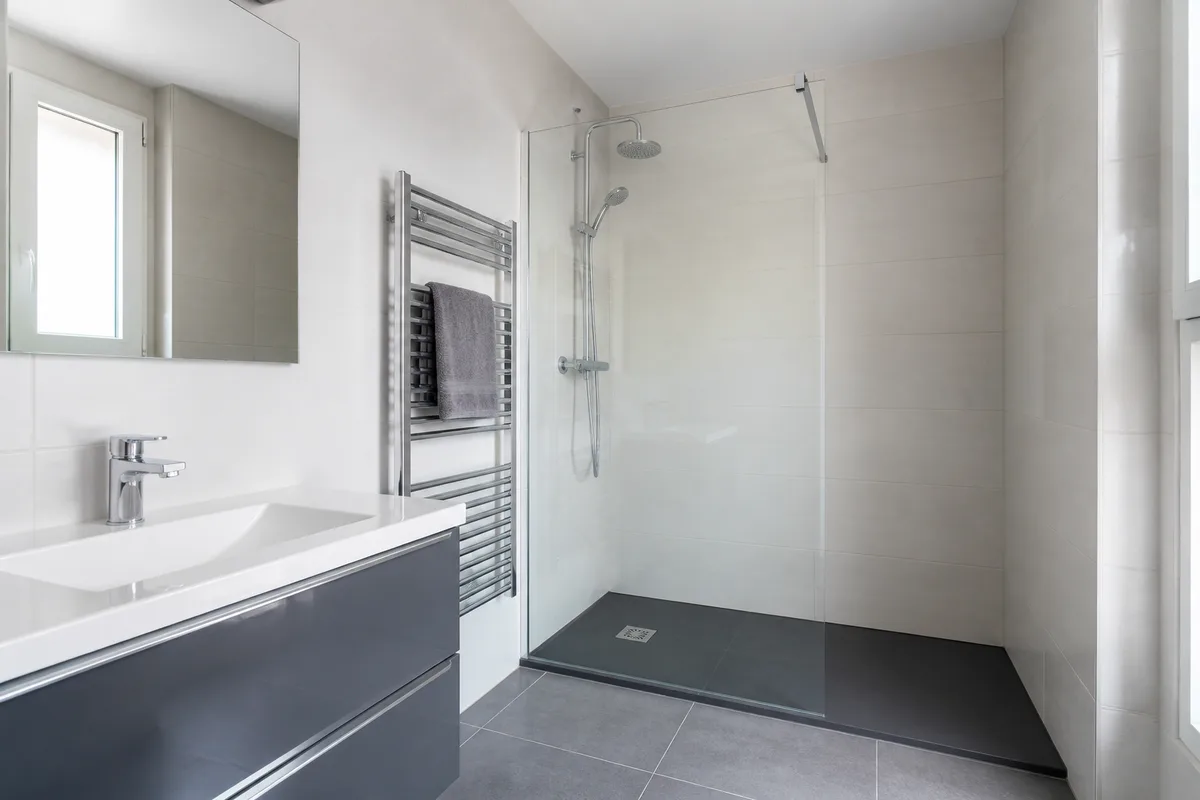 Salle de bain renovee avec carrelage clair et robinetterie chromee en lumiere naturelle